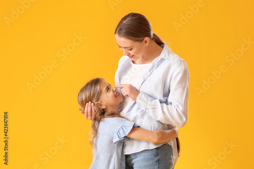 Happy woman and her little daughter on color background