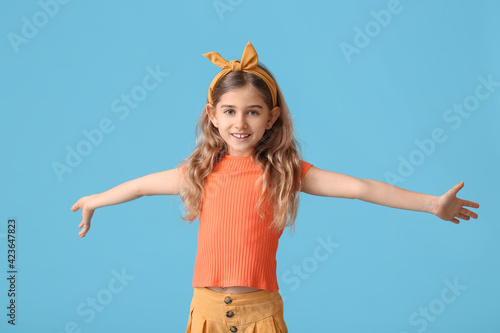 Little girl opening arms for hug on color background