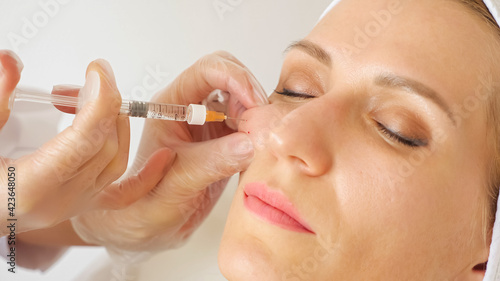 Close-up of a beautician giving an injection into the cheek of a woman.