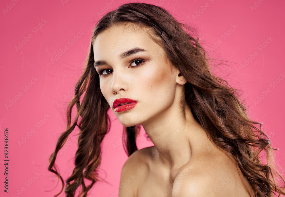 Sexy brunette with loose hair on a pink background with bright makeup Sexy brunette with loose hair on a pink background with bright makeup