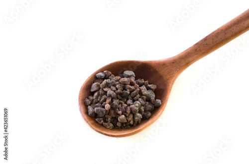 A spoon of black salt on white.