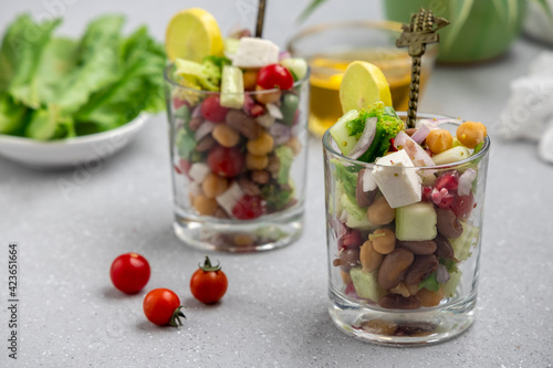 fresh green salad served in small transparent glass with beans, legumes, and pomegranate seeds