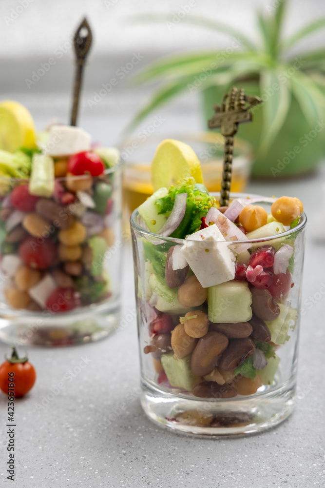 fresh green salad served in small transparent glass with beans, legumes, and pomegranate seeds fresh green salad served in small transparent glass with beans, legumes, and pomegranate seeds