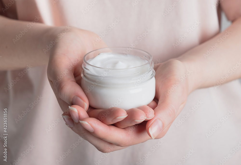 Woman holding cosmetic cream in open jar. Facial or hands skincare, moisturizing, beauty treatment concept. Close up Woman holding cosmetic cream in open jar. Facial or hands skincare, moisturizing, beauty treatment concept. Close up