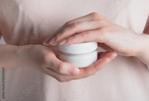 Woman hands holding cosmetic cream in glass jar. Skincare, moisturizing, beauty concept. Close up