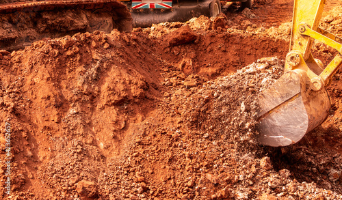 Backhoe digging soil at construction site. Bucket of backhoe digging soil. Crawler excavator digging on dirt. Excavating machine. Earth moving machine. Excavation vehicle. Backhoe working on suny day. photo