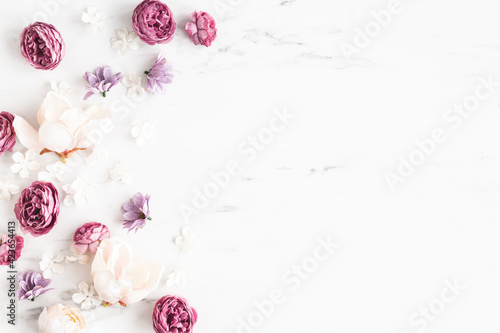 Flowers composition. White and purple flowers on marble background. Flat lay, top view