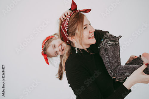 Mother and daughter in same clothes family look having fun together. Pregnant woman with daughter on white background. 