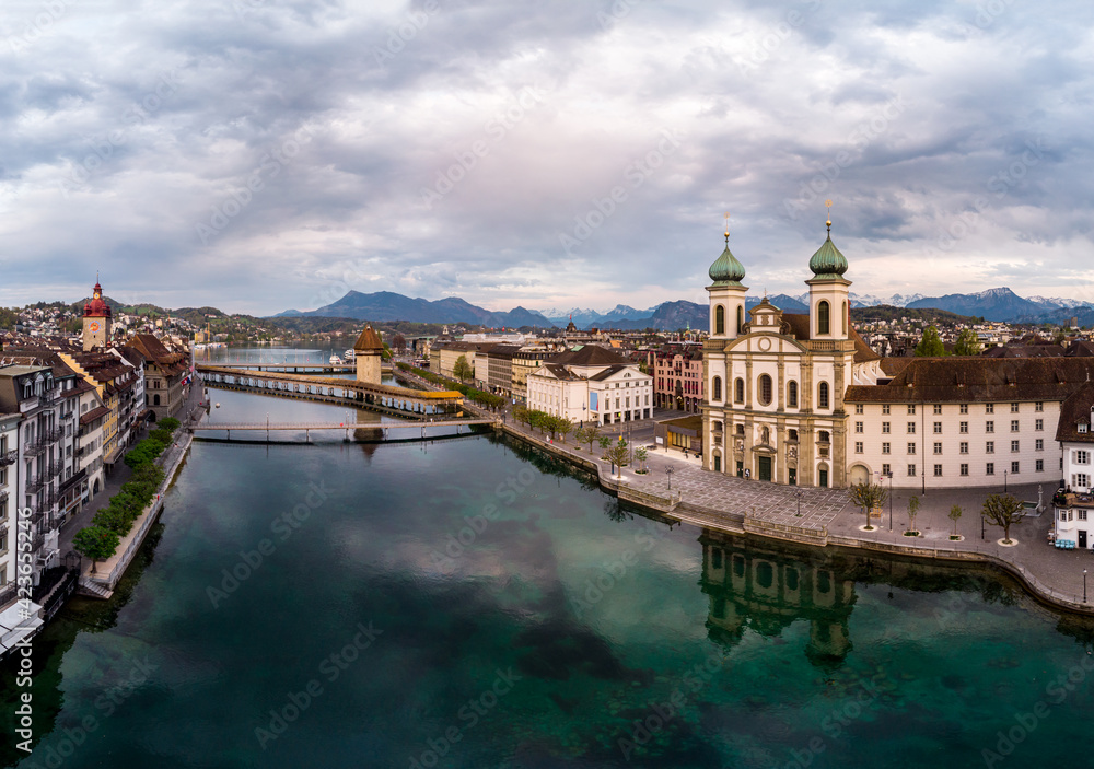 Dramatic aerial view of the Reuss river in the heart of Lucerne old town with the Jesuit church and the chapel's bridge in Switzerland