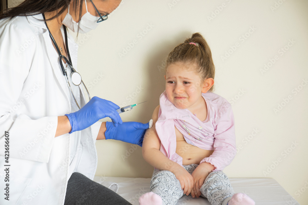 chubby little girl in pediatric examination by her doctor. vaccinated by her doctor. little girl worried and scared. Selective Focus chubby little girl in pediatric examination by her doctor. vaccinated by her doctor. little girl worried and scared. Selective Focus