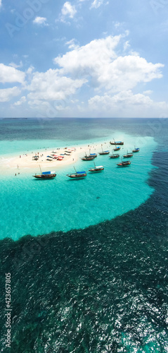 View from above or from a bird's eye view of the coral island, the white sand beach and the beautiful, clear turquoise waves with boats.