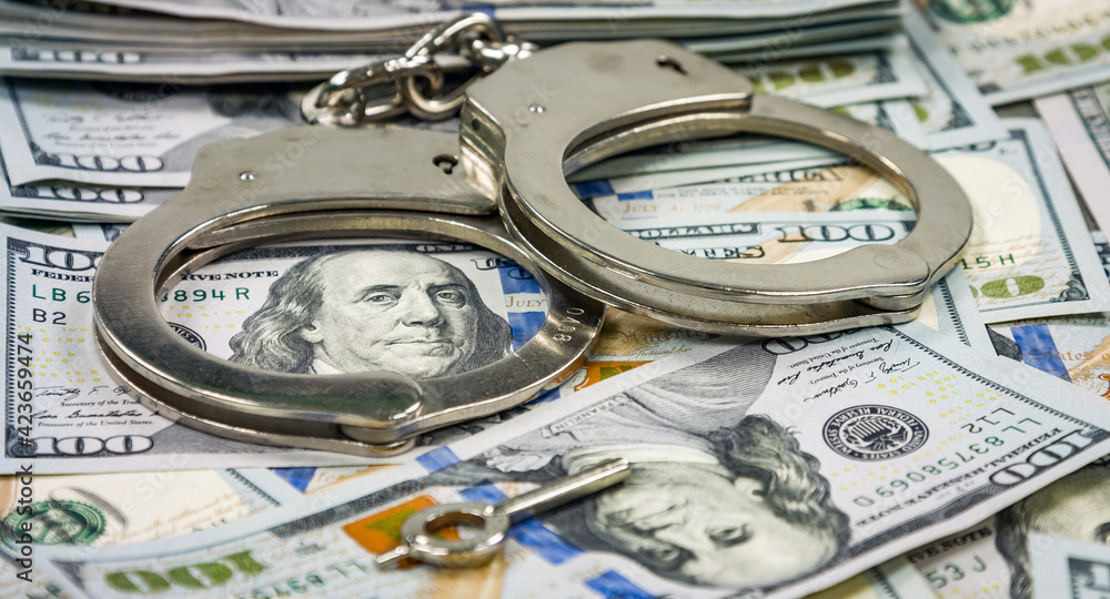 Pair of handcuffs closeup on dollar banknotes background. Corruption problem Pair of handcuffs closeup on dollar banknotes background. Corruption problem
