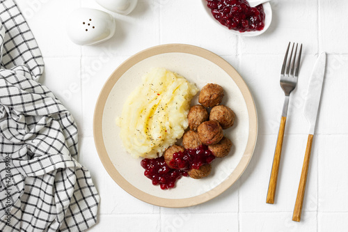 Swedish meatballs with mashed potatoes and lingonberry jam top view. A traditional Scandinavian dish in a ceramic plate on a white kitchen table