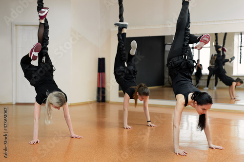 Close-up group of girls hanging on bungee rubber bands in the gym. Girls perform a difficult exercise with bungee gum