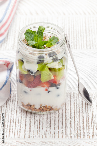 Healthy breakfast with jar of granola, yogurt and fresh berries