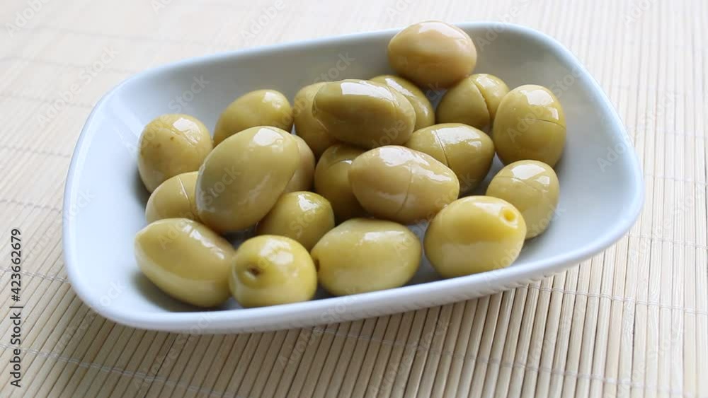 green olives in a bowl, with olive oil green olives in a bowl, with olive oil