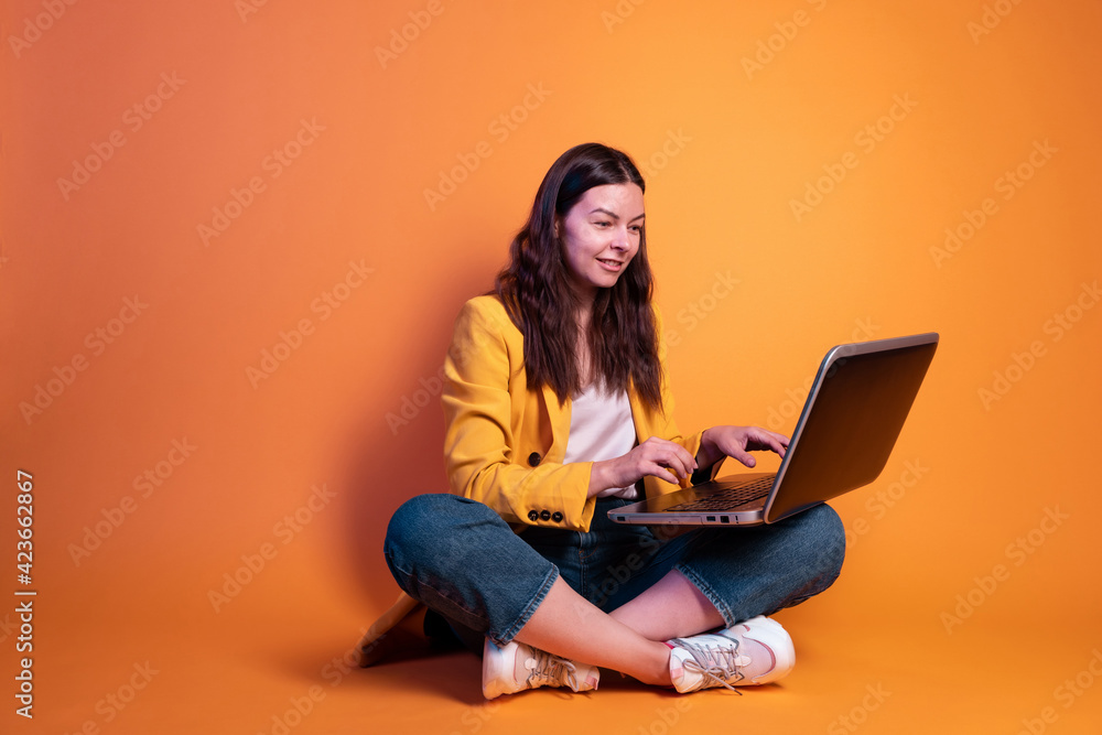 Naklejka premium freelancer at a laptop, a young specialist working remotely. A young woman in modern-style clothing