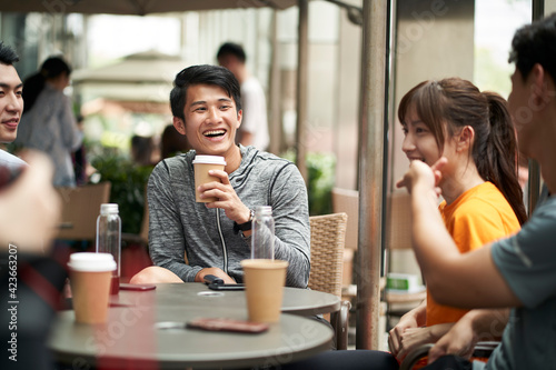 group of happy young asian adults man and woman relaxing at outdoor coffee shop