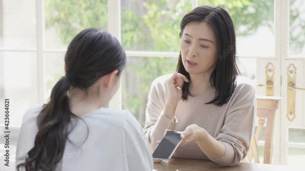 スマホを見せながら子供を叱るミドル女性 スマホを見せながら子供を叱るミドル女性