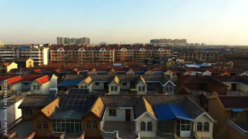 In early morning, sun passing above residential houses in a town in China. Town gradually brightens. In early morning, sun passing above residential houses in a town in China. Town gradually brightens.