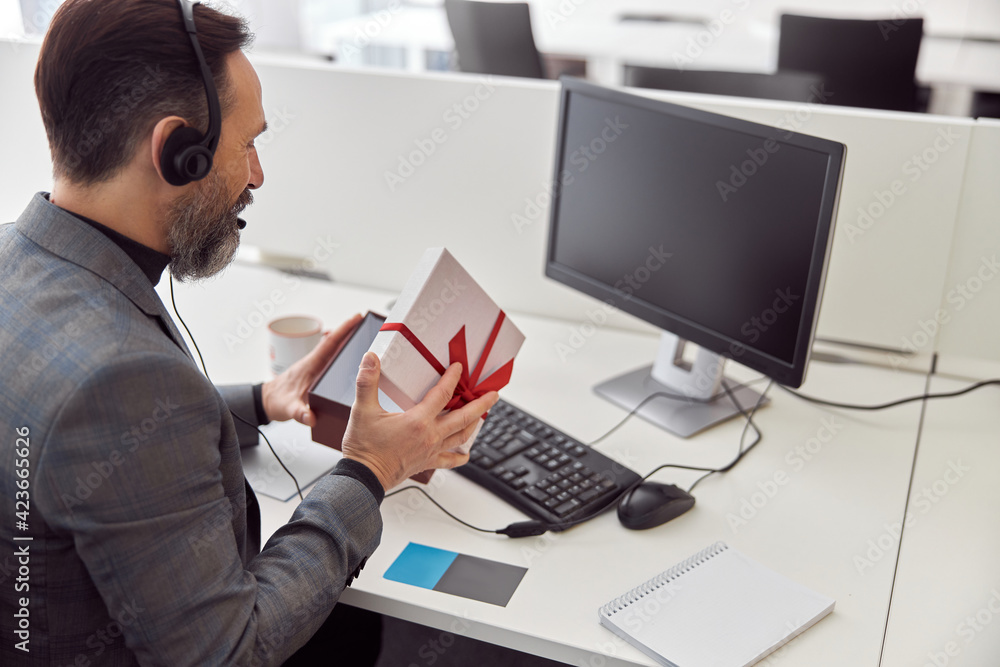 Happy office worker is holding a present and smiling Happy office worker is holding a present and smiling