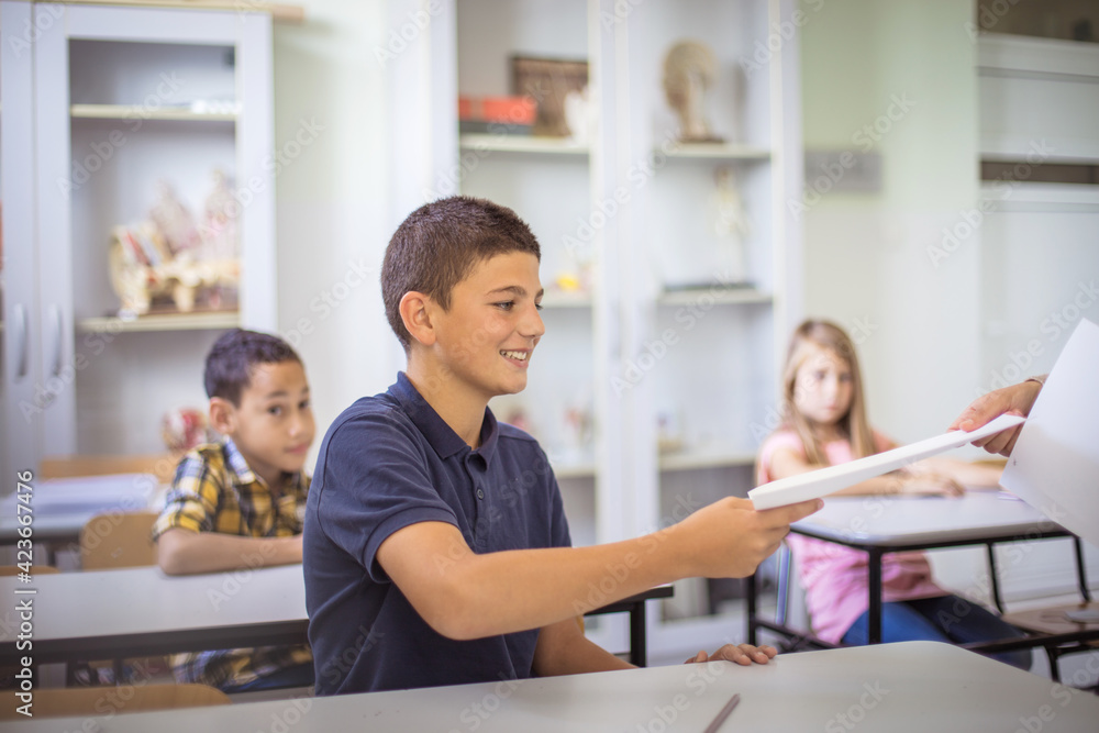 He is happy for the good grade. Teens in class. The teacher gives them control tasks. He is happy for the good grade. Teens in class. The teacher gives them control tasks.
