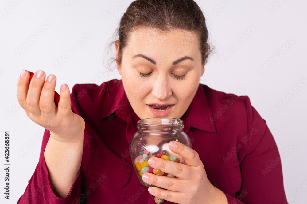 Close-up portrait of plus size nice attractive charming sweet cute cheerful cheery dreamy plump woman smelling sweet candies in opened glass jar isolated on gray background Close-up portrait of plus size nice attractive charming sweet cute cheerful cheery dreamy plump woman smelling sweet candies in opened glass jar isolated on gray background