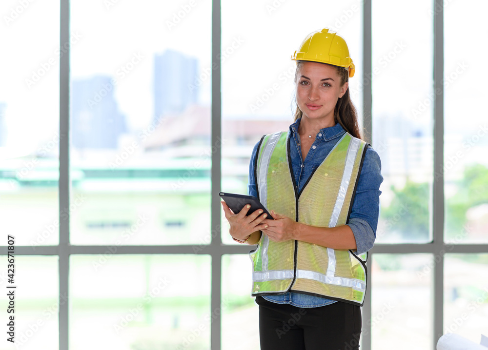 Portrait of female construction engineer workers in yellow hardhat with a tablet computer in construction site Portrait of female construction engineer workers in yellow hardhat with a tablet computer in construction site