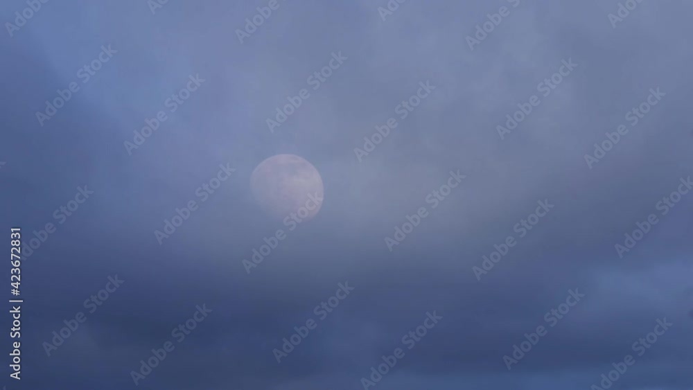 Moon rising through blue cloudy skies Moon rising through blue cloudy skies