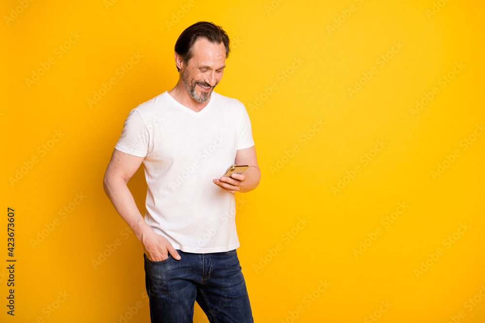 Portrait of attractive cheerful focused guy using device media multimedia comment isolated over bright yellow color background Portrait of attractive cheerful focused guy using device media multimedia comment isolated over bright yellow color background