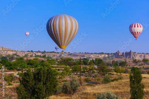 Hot air balloon flying over rocky landscape at sunrise - Cappadocia Turkey