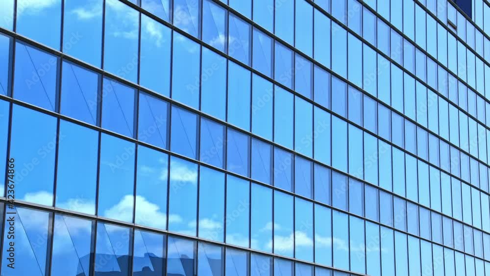 Time-lapse shot of floating white clouds under blue sky reflected on clear windows of a high-rise building Time-lapse shot of floating white clouds under blue sky reflected on clear windows of a high-rise building