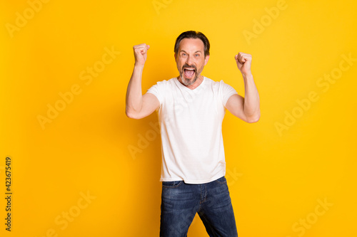 Photo of happy cheerful crazy mature man raise fists winner celebrate isolated on yellow color background