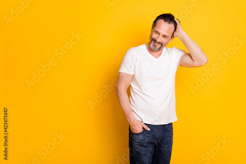 Photo of handsome charming man look empty space hold hand pocket hair isolated on yellow color background