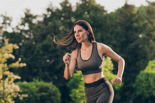 Photo of nice optimistic brunette lady run hands fists wear sport cloth do fitness outdoors in park