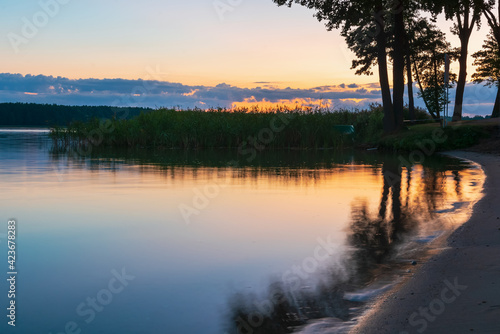 Wallpaper Mural calm lake and sand shore with trees and dark blue sky, tranquil nature landscape at night Torontodigital.ca