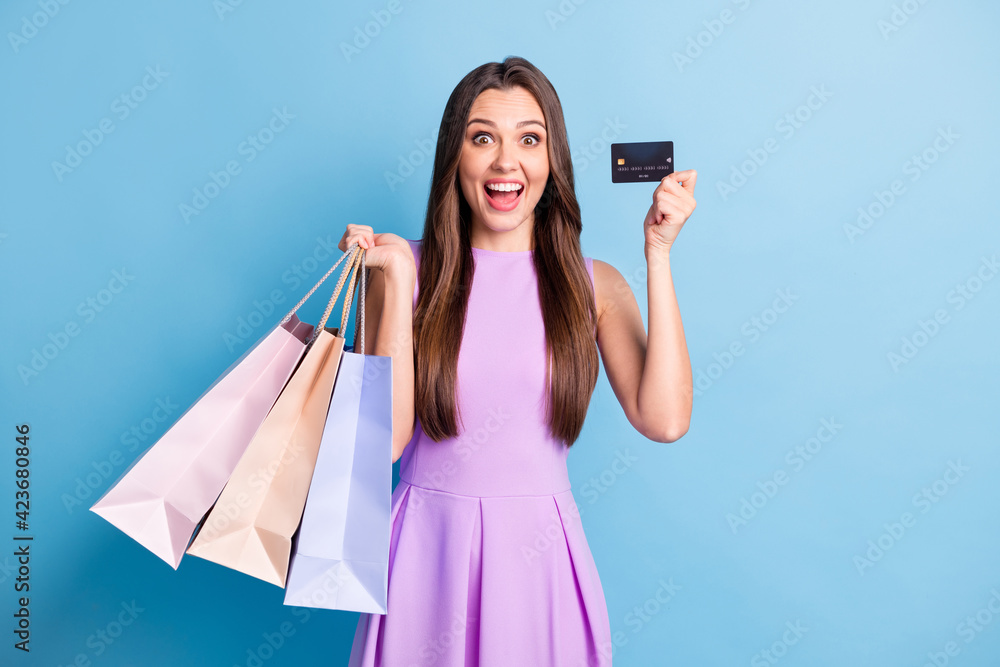 Photo of excited crazy girl hold debit card packets beaming smile wear purple dress isolated blue color background Photo of excited crazy girl hold debit card packets beaming smile wear purple dress isolated blue color background