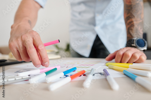Close-up image of graphic designer using felt tip pens of various color when coloring logo mockup