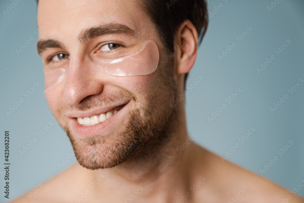 Shirtless white man with under eye patches smiling at camera Shirtless white man with under eye patches smiling at camera