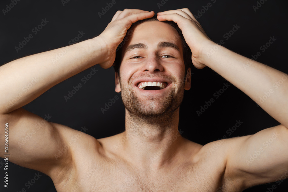 Shirtless white man smiling while holding his head Shirtless white man smiling while holding his head