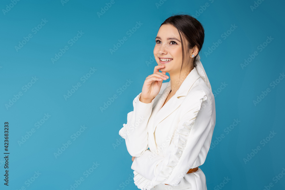 Portrait of a cute young business lady posing in a white shirt with a smile on a blue background. Successful young people. Studio background with empty space. Portrait of a cute young business lady posing in a white shirt with a smile on a blue background. Successful young people. Studio background with empty space.