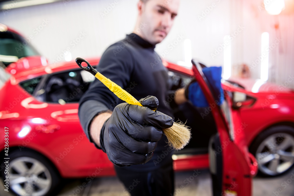 Car service worker cleans interiror with special brush Car service worker cleans interiror with special brush