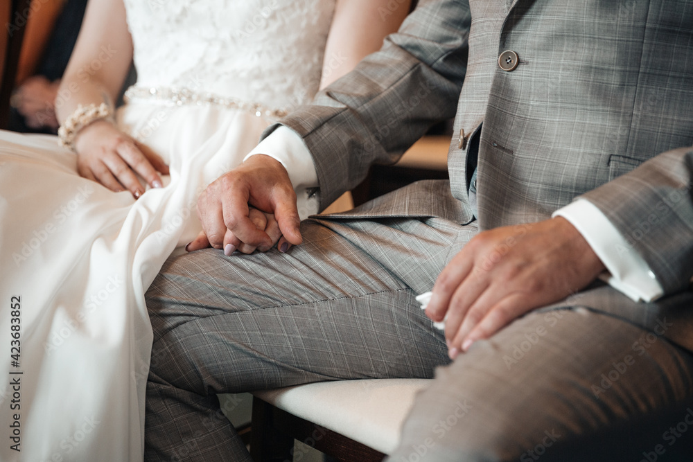 Groom and bride holding hands during wedding ceremony