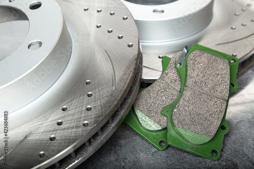 brake pads and perforated brake discs on a stone gray table