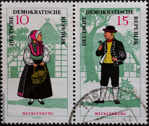 GERMANY, DDR - CIRCA 1966  : a postage stamp from Germany, GDR showing a woman and a man in the folk costume of Meklenburg. In front of a half-timbered house photo