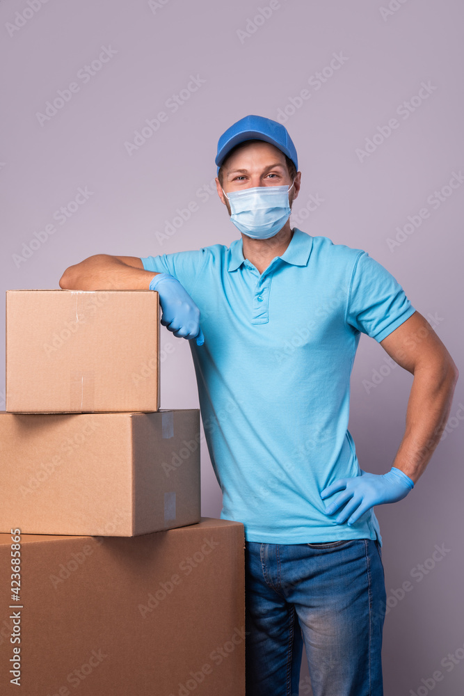 Young delivery man is wearing prevention mask and gloves with a cardboard boxes Young delivery man is wearing prevention mask and gloves with a cardboard boxes