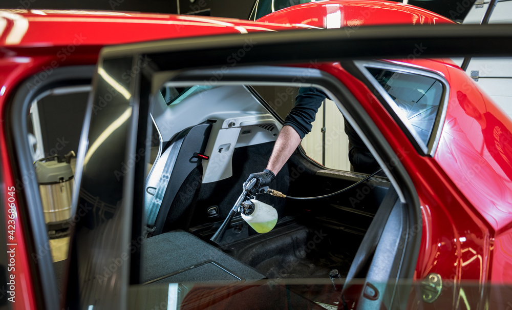 Fototapeta premium A car service worker cleans interiror with a special foam generator