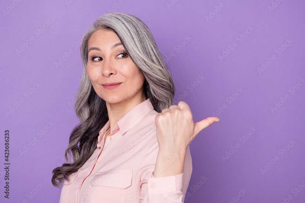 Profile side view portrait of attractive trendy elderly retired woman demonstrating copy space ad isolated over violet purple color background Profile side view portrait of attractive trendy elderly retired woman demonstrating copy space ad isolated over violet purple color background