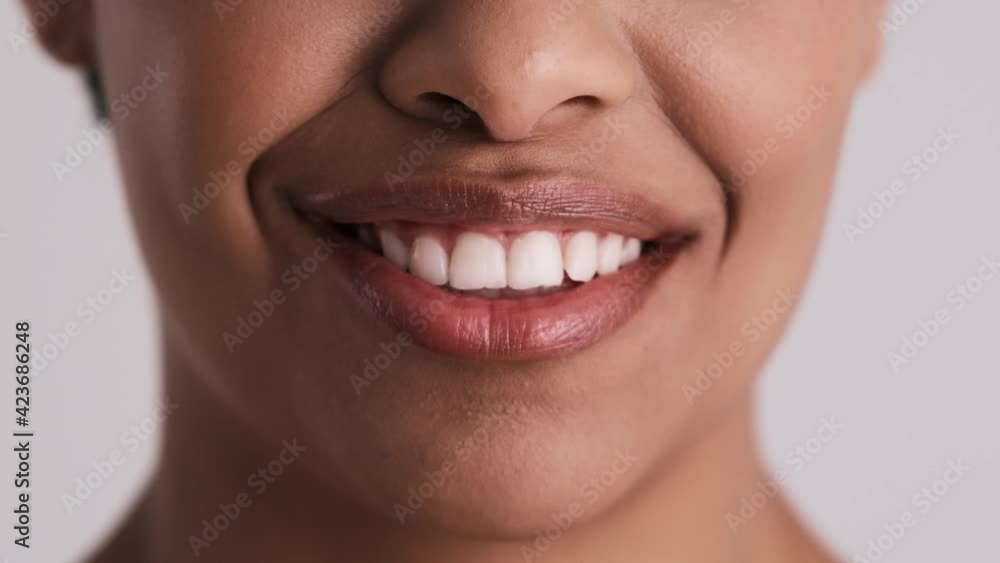 A close-up cropped view of a surprised woman's mouth isolated over a gray background in the studio A close-up cropped view of a surprised woman's mouth isolated over a gray background in the studio