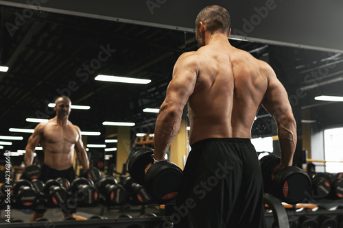 Muscular bodybuilder in a free weights zone in the gym